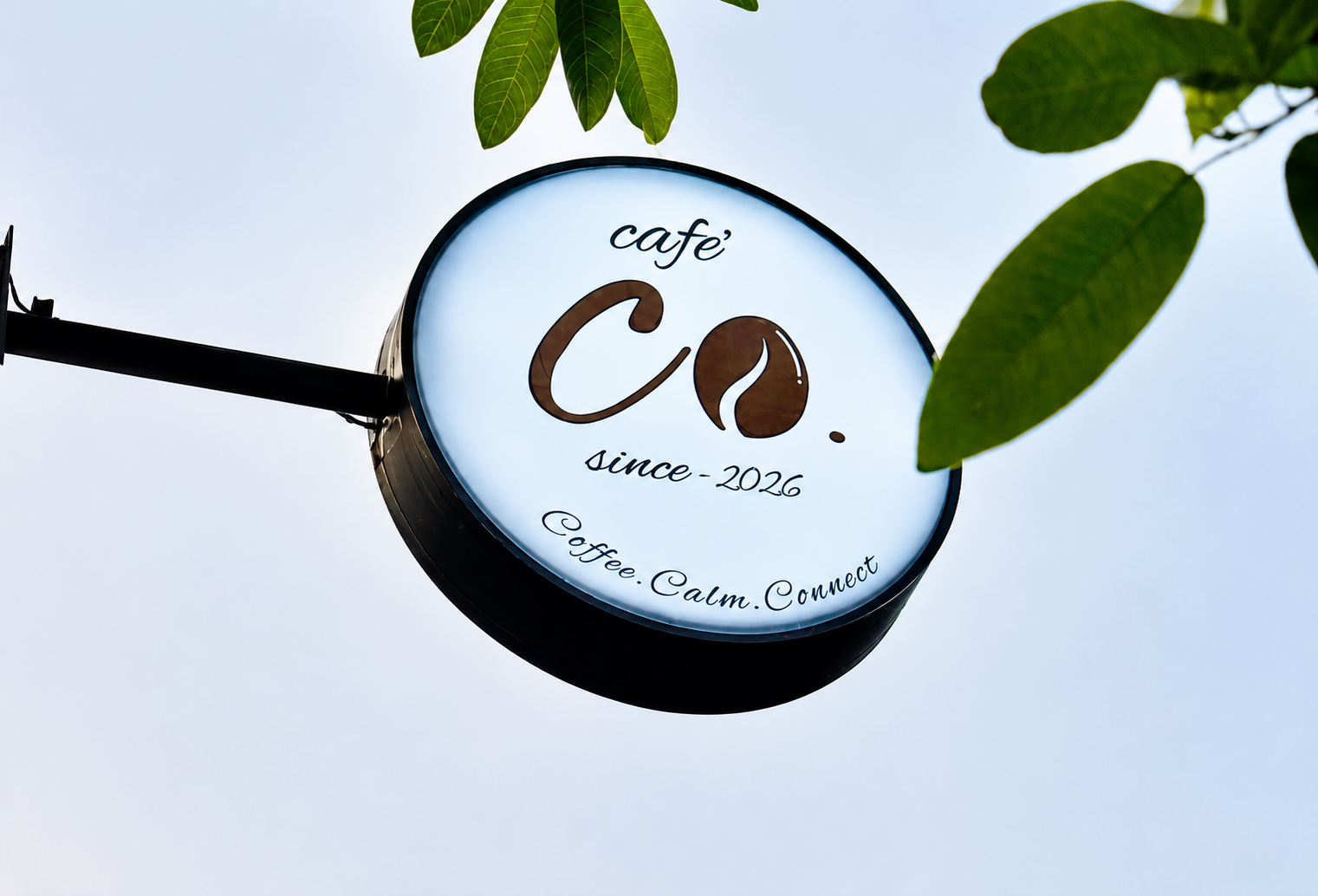 Cafe' Co. hanging sign with leaves against the sky